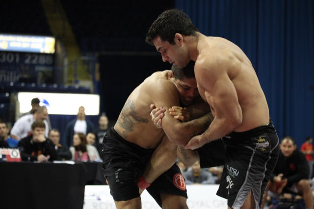 Two BJJ fighters. One is using an arm drag on his opponent.